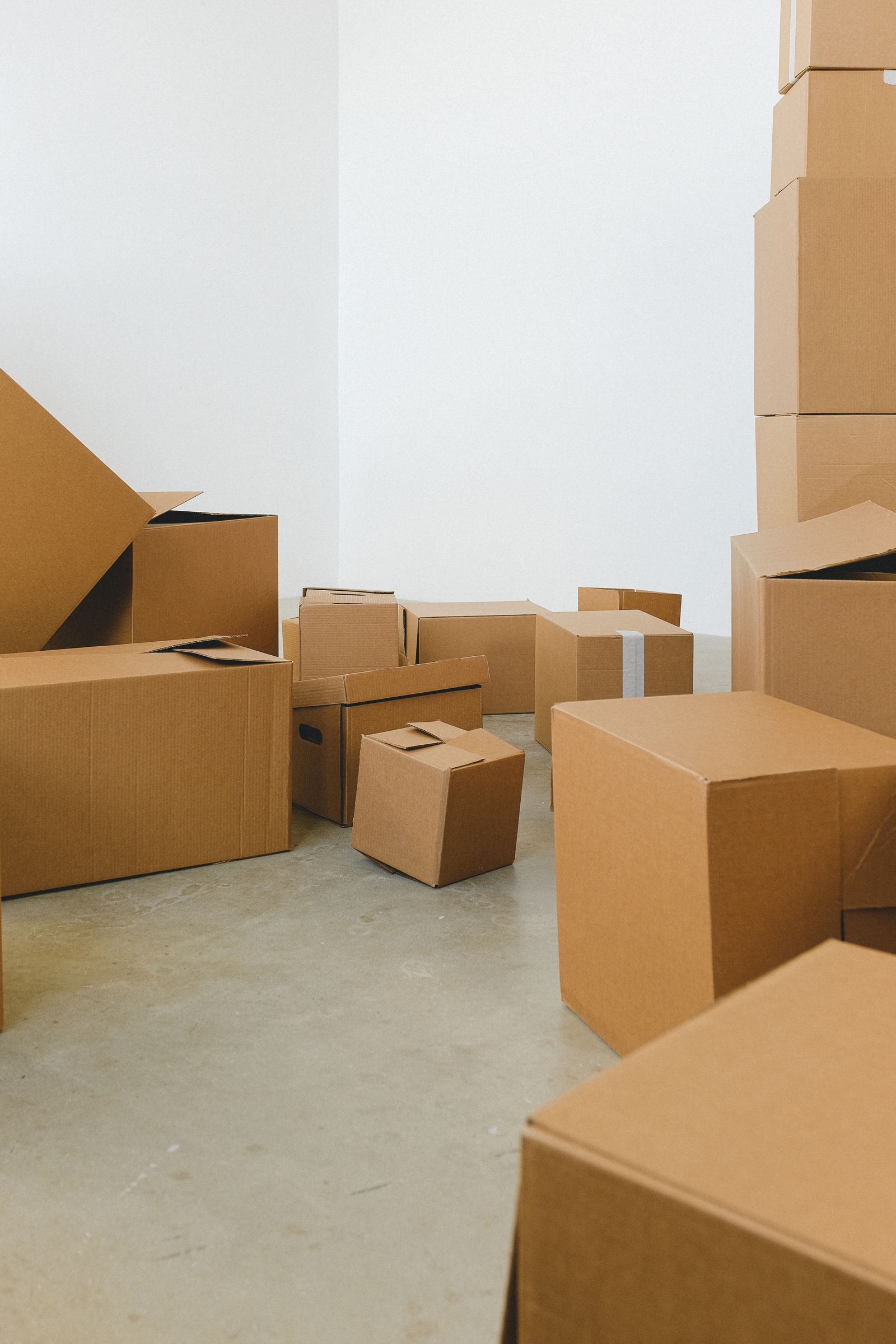 Cardboard boxes stacked on the floor of a bright, emptying room