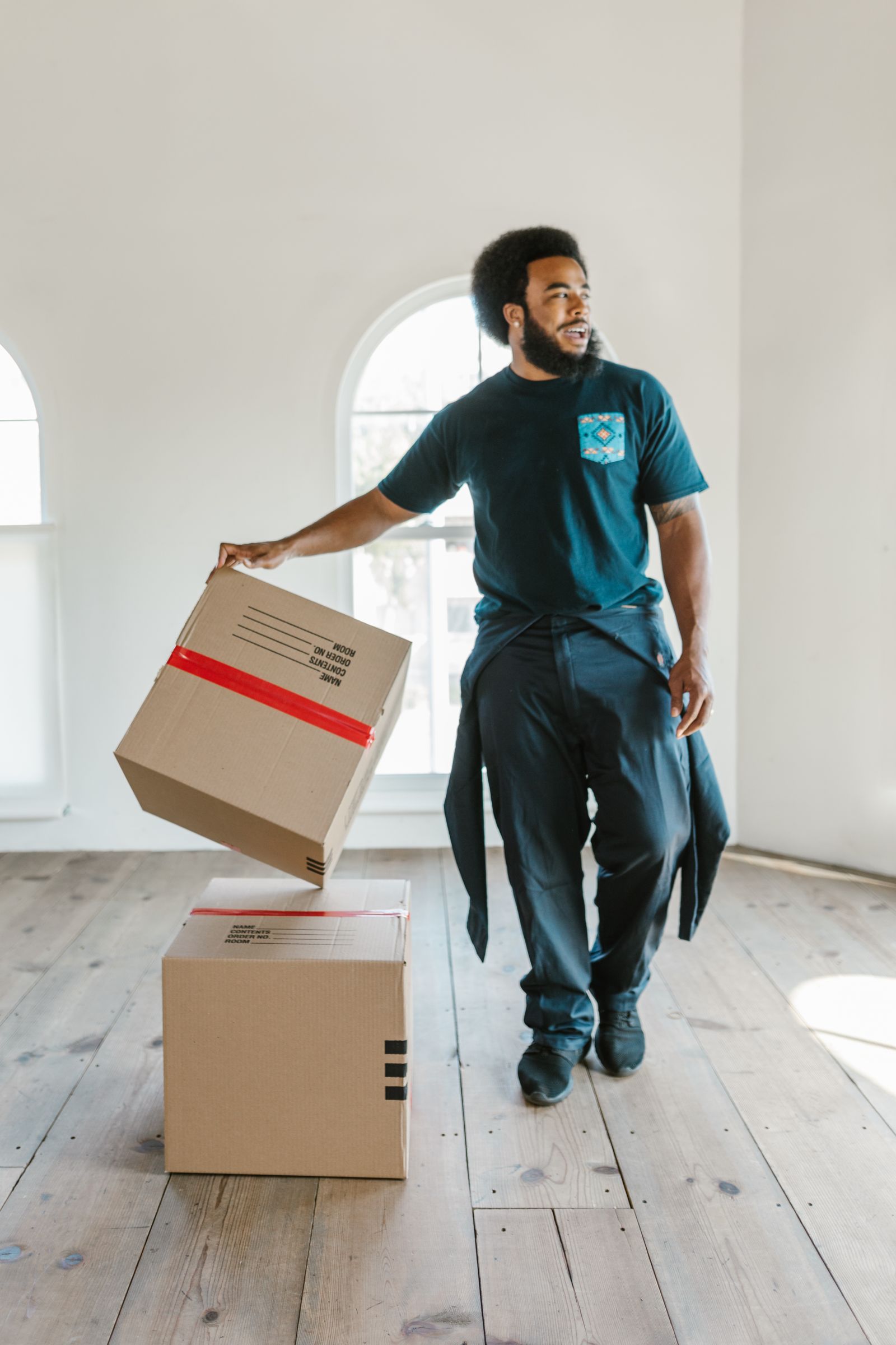 A mover handling a cardboard box in a bright, empty room